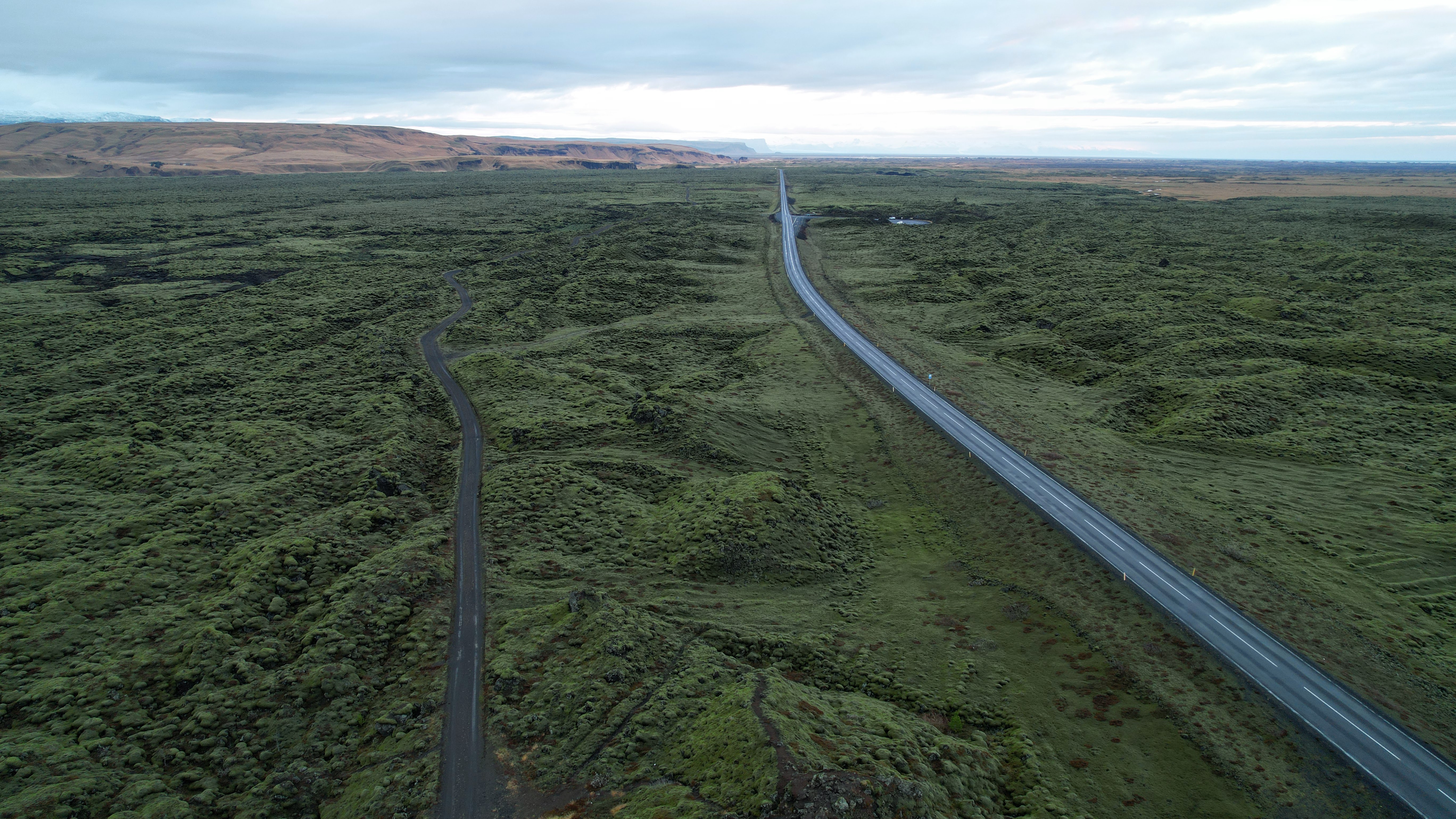 An image from a drone of a road in southern Iceland with fields of moss on either side